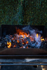 Charcoal and embers burning at full capacity at its peak in a metal barbecue and smoke