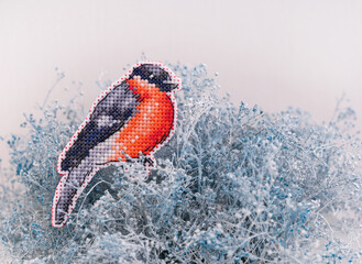 A cross stitched bullfinch on white and blue dried Gypsophila. A bird embroidered by myself.
