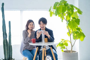 明るいリビングでスマホで動画を見る若い夫婦