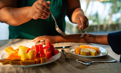 brown skinned south Asian mom serving fresh fruits to a kid for morning breakfast as healthy meal using folks,