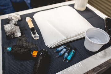 Closeup of a work table of a tattoo artist with tattoo machine, needles, plastic ink containers...