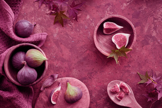 Viva Magenta color of the year 2023. Fresh halved fig fruits and dry eucalyptus and cala lily flowers painted metallic pink on bstract textured background.