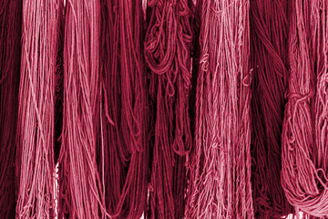 Colorful skeins of silk thread to create traditional Turkish carpet on a loom. New 2023 trending PANTONE 18-1750 Viva Magenta colour
