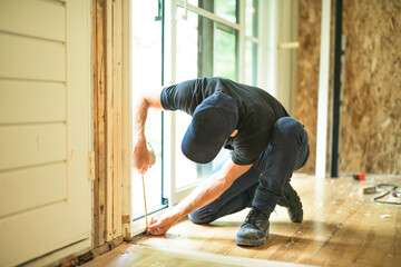 A handsome man installing Double Sliding Patio Door in a new house construction site