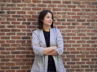 brunette girl leaning against brick wall.