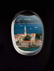 Old town of Budva, top view from porthole window of airplane, Montenegro. Concept for travel company or airway transportation.