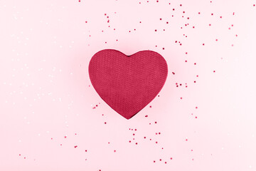 Gift box in the form of a viva magenta heart on a magenta background with sequins