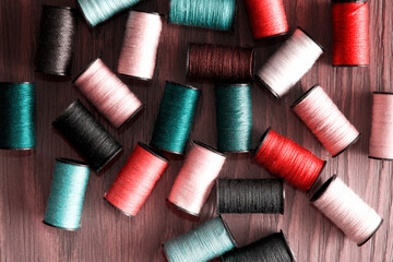 Pink and turquoise colored thread reels scattered on the tailor table. Embroidery theme backgrounds