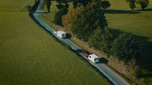 Two electric cars towing caravans on a country road