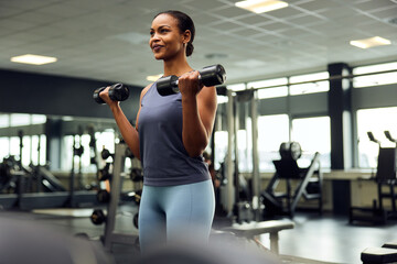 Smiling woman lifting weights at the gym