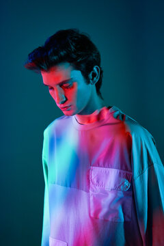 Young man in straitjacket standing against neon illumination