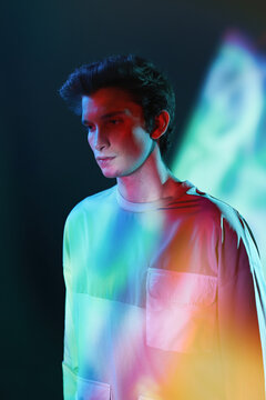 Young man in straitjacket standing against neon illumination