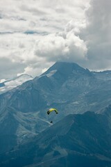 Vertical shot of a man on a paraglider with Schmittenhohe mountains in the background, Austria