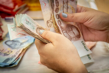 Hands counting of Thai baht notes money, banknotes paying - obrazy, fototapety, plakaty