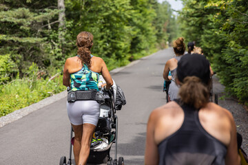 Backside photo taken from mom instructor walking together with other new mothers in a group session...