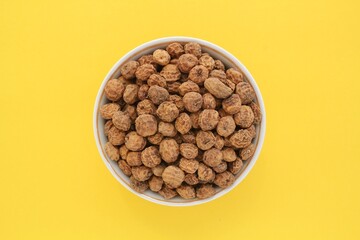 Chufa, tigernut, earth almond on ceramic bowl on yellow background. Healthy organic food concept. Tiger nut for flour, milk, traditional typical homemade cold fresh drink horchata from Valencia Spain