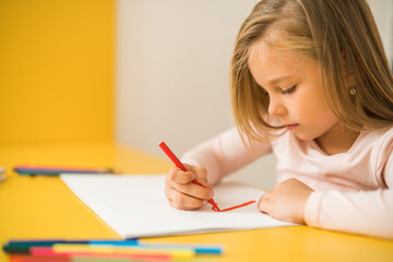 Beautiful little girl enjoys drawing at her home.	