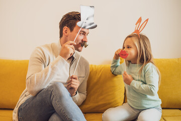 Father and daughter having fun with  party props at their home.