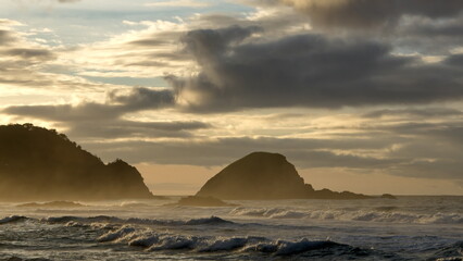 Sunrise casting a golden glow over an islet and the beach in Zipolite, Mexico