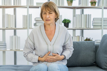 Flatulence caucasian mature adult, senior woman hand in stomach ache, suffer from food poisoning,...