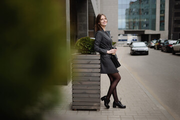 Happy woman in business clothes and relaxing with a folder of documents and coffee after a successful business meeting.