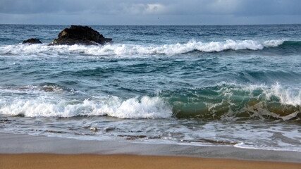 Waves breaking on the beach, with a rock just offshore, in Zipolite, Mexico