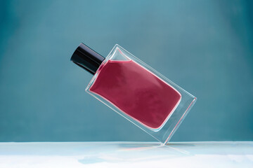 Suspended magenta glass perfume bottle on blue background
