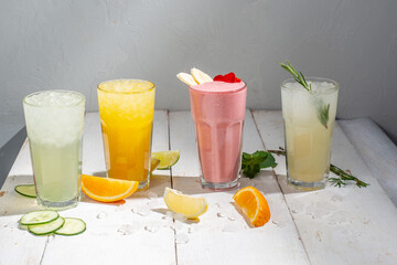 Many different cocktails and milkshakes on a light background. Colored  non-alcoholic cocktails and lemonades in tall glasses