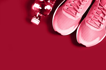 Sneakers and bottle of water on red background. Concept of healthy lifestile, everyday training and force of will. Demonstrating Viva Magenta - trendy color of the year 2023