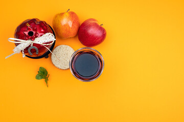Apples, pomegranate, traditional bread, greens with a glass of red wine. The concept of the Jewish New Year Rosh Hashanah on a yellow background