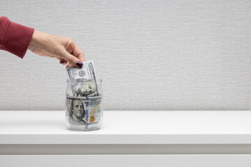Man puts money in a glass jar.