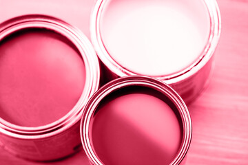 Several opened cans with paint inside. red and white colors of paint. Close up. Demonstrating Viva Magenta - trendy color of the year 2023 - 550914297