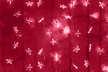 Silver star garland on red background. Demonstrating Viva Magenta - trendy color of the year 2023