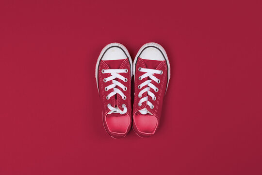 Red sneakers top view close up on colorful background. Color of the year 2023, viva magenta.