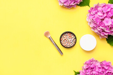 Obraz na płótnie Canvas Makeup accessories. Set of decorative cosmetics makeup brushes, blush face balls, pink hydrangea flowers on yellow background top view Flat lay copy space. Beauty blogger concept. Fashion background