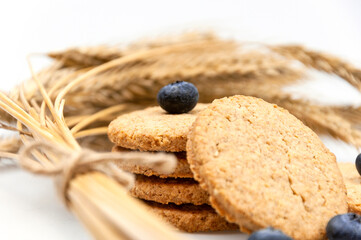 Cookies with bran and blue berries on a white background with rye ears.