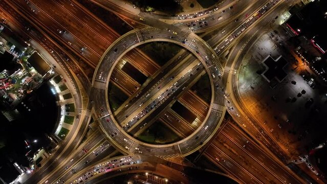 Aerial drone time lapse night video of illuminated multi level ring highway road passing through busy city centre