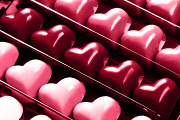 Black opened box with chocolate red hearts, close up. St. Valentine's Day Concept. Demonstrating Viva Magenta - trendy color of the year 2023