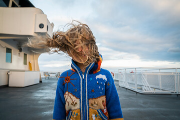 A young girl on ferry boat deck with wind blowing her hair