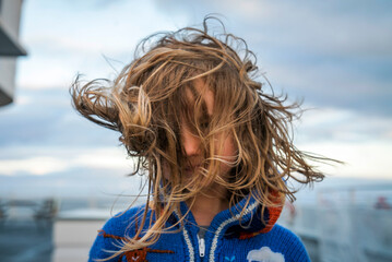 A young girl on ferry boat deck with wind blowing her hair