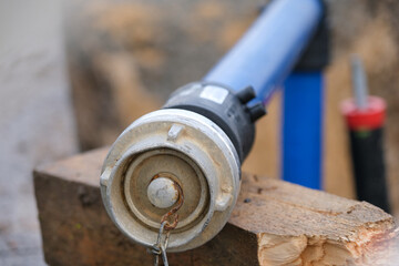 Nahaufnahme auf einen Wasseranschluss mit Absperrventil und Rohr in einer Baugrube auf einem Holzbalken, selektiver Fokus, viel Copy Space