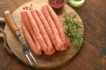 Meat beef sausages. Raw barbecue sausages with spices, vegetables and ingredients for cooking on black background. Top view. Copy space. Oktoberfest menu concept.
