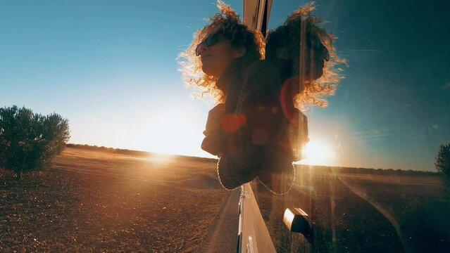 Happy tourist enjoy travel road trip and have fun in vanlife adventure lifestyle. One cheerful woman outside the vehicle window during sunset sunlight time in holiday vacation journey