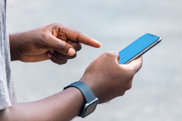African black man pointing finger at blank screen smart phone, with smart watch street lifestyle, blurred background