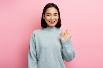 Portrait of satisfied beautiful young woman standing, looking at camera showing Ok