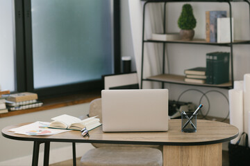 Stylish workspace loftspace with laptop, notebooks on wooden table with blurred office room background office supplies,  work concept, work from home