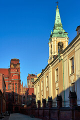 Fototapeta na wymiar The belfry of a church and facades of historic tenement houses in Torun
