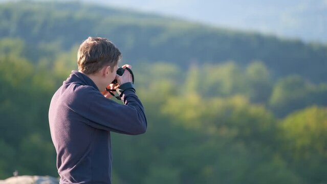 Hiker photographer taking pictures of morning nature in summer mountains