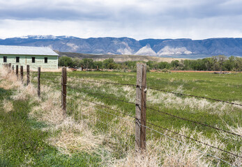Fototapeta na wymiar Farmland in Shell, Wyoming, from fence to Bighorn Mountains in the background. You can see moraines, alluvial fans, and nearby pasture land with farm building.
