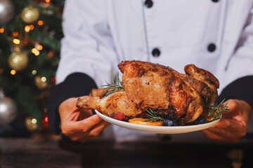 Close up Chef hands holding roasted chicken on a plate.